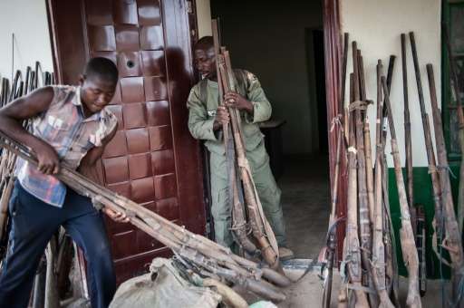 Ranger Hashumu Abdullahi (C), known as 'The Armorer' and his assistant, unpacking some of the over 200 confiscated locally made 