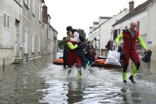 Rescuers evacuates residents accross a flooded street on June 1, 2016 in Souppes-sur-Loing, southeast of Paris