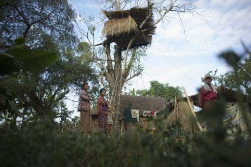 Residents stand near a tree house in the Kyauk Ye village on the outskirts of Yangon on January 14, 2016