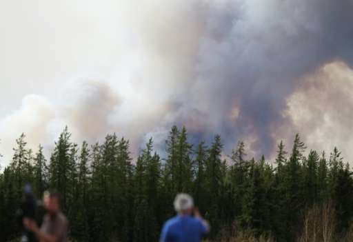 Smoke rises off Highway 63 on May 7, 2016 outside Fort McMurray, where raging forest fires have forced more than 88,000 from the