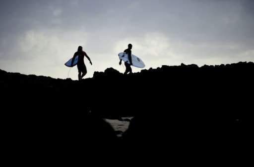 Surfers make their way over rocks to surf in Ballina, the Australian town now infamous for a  spate of shark attacks