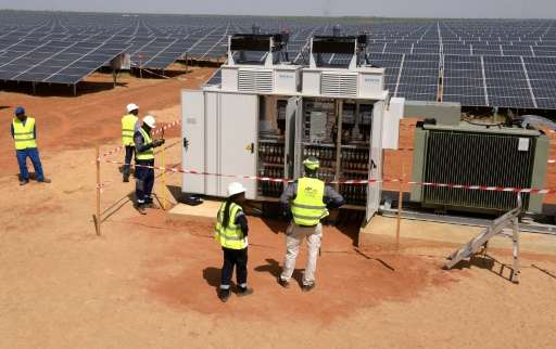 Technicians operate electrical cabinets on October 22, 2016 during the opening ceremony of a new photovoltaic energy production 