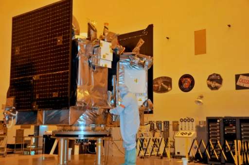 The OSIRIS-REx spacecraft sits on its workstand while an engineer checks the protective covering in a servicing building at Kenn