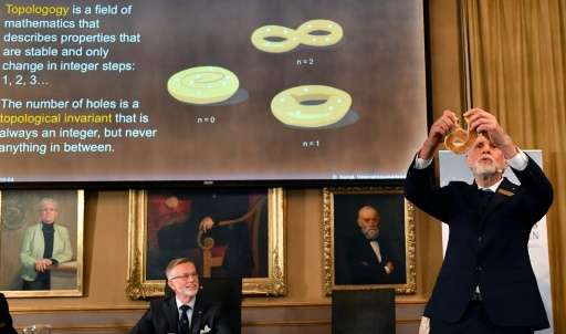Thors Hans Hansson (R), member of the Nobel Committee for Physics, uses a pretzel to visualize his explanations during a press c