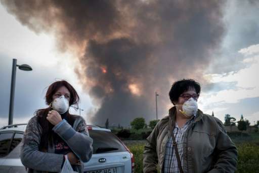 Two neighbours in Sesena, near Madrid wear masks as they wait for relatives to evacuate a residential area affected by toxic fum