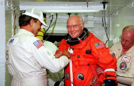 US astronaut and Senator John Glenn getting a hand from white room technicians moments before boarding the US space shuttle Disc