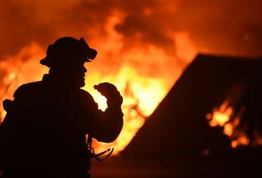 A firefighter drinks water in front of a burning house near Oroville, California on July 9, 2017. Crews are battling the season'
