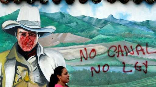 A woman is seen in front of a wall with a graffiti reading &quot;No canal, no law&quot; during a protest against the constructio