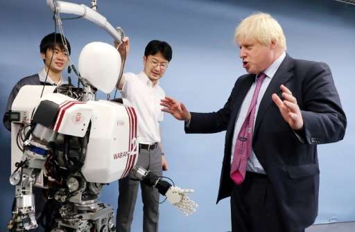 Britain's Foreign Secretary Boris Johnson (R) looks at the humanoid robot Wabian II, which resembles a tiny astronaut that Wased