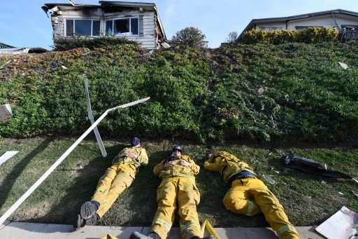 Exhausted firefighters have their first rest in over 20 hours since starting to fight the Lilac Fire, December 8, 2017, in Bonsa