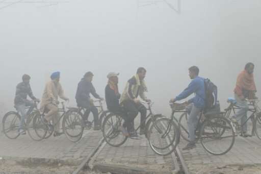 Indian commuters ride over tracks at a railway crossing amid heavy smog in Amritsar