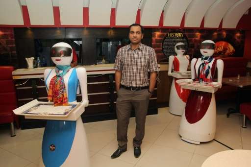 In this photograph taken on July 4, 2017, Pakistani engineer Osama Jafari (C) poses with robot waitresses Annie (L), Rabia (R) a