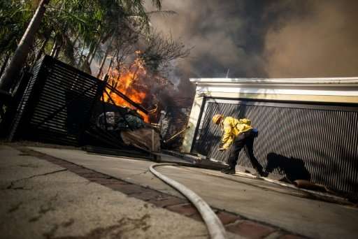 Firefighters work to save burning houses in the Skirball Fire near Los Angeles