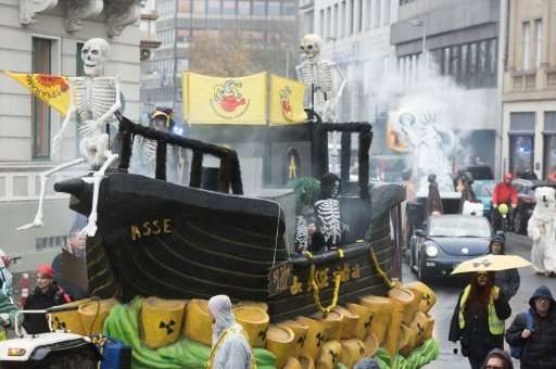 Demonstrators dressed as human skeletons stand on a ship-designed float swimming on symbolical nuclear waste during a protest of