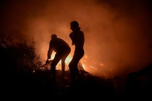 Firefighters and civilians tyring to subdue a blaze in Vigo, northwestern Spain, on Sunday