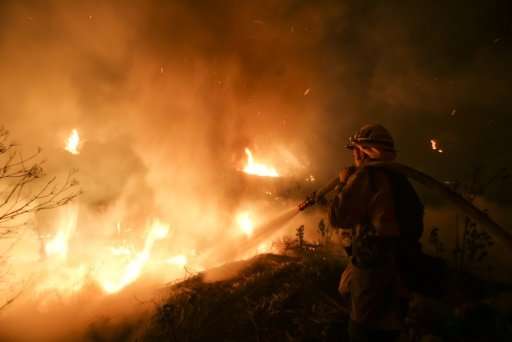 Firefighters battle flames on a hillside near homes in Santa Paula, California, as the Los Angeles region grapples with wind-whi