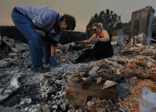 Members of the Reinhardt family sort through the remains of their family home after the Thomas wildfire swept through Ventura, C