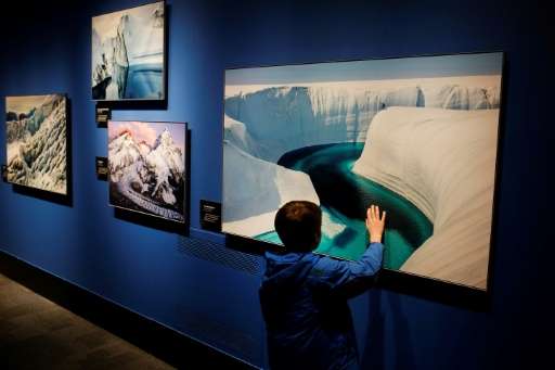 A boy touches one of the photos displayed at the &quot;Extreme Ice&quot; exhibit by US photographer James Balog at the Museum of