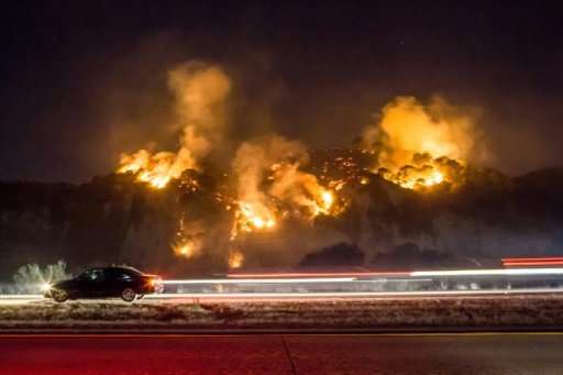 A car drives past as the Thomas Fire burns a hillside south of Casitas Springs, California