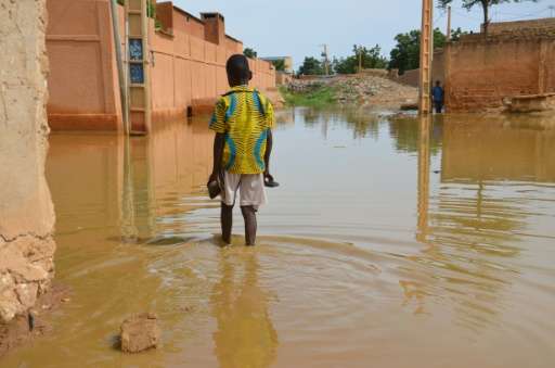 A child walks in muddy water in the Saga district of Niamey on September 11, 2017 as streets are flooded by the overflowing Nige