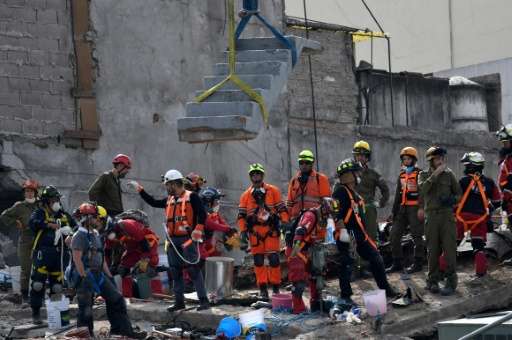 A crane removes concrete stairs as rescuers pause at the remains of a quake-stricken building at Colonia Roma in Mexico City