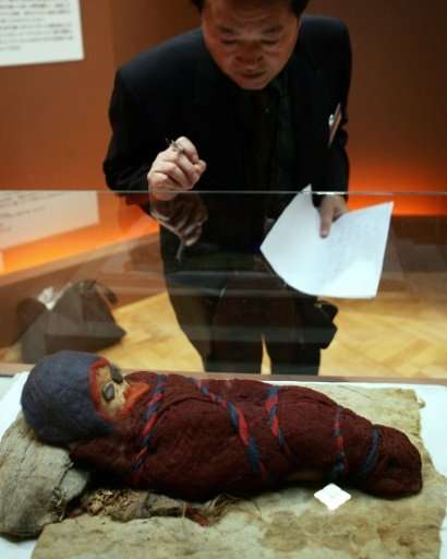 A journalist looks at a baby mummy which was unearthed at an ancient tomb in Chinese city of Qarqan. The Kyrgyzstan mummy &quot;