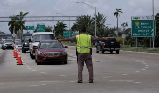 A law enforcement officer directs traffic at a checkpoint preventing residents of the Florida Keys from returning to their homes