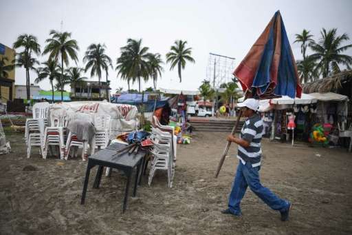 A man carries an umbrella while dismantling his beach business in anticipation of the arrival of Tropical Storm Franklin in the 
