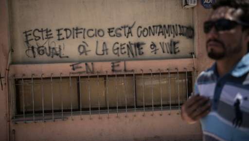 A man walks past graffiti reading &quot;This building is contaminated, as well as the people living in it&quot; in Chile's port 