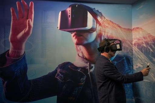 A man wearing a VR headset experiments with a merged reality experience using Project Alloy at the Intel exhibit during the 2017
