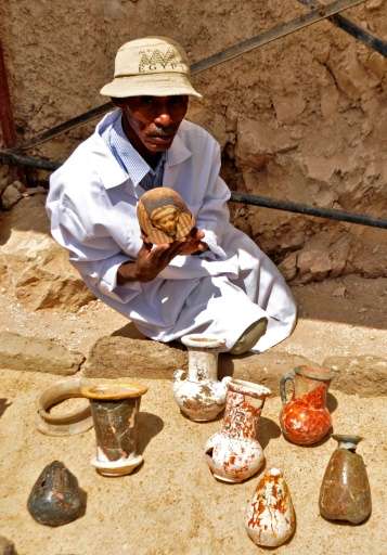 A member of an Egyptian archaeological team shows artifacts discovered in a 3,500-year-old tomb in the Draa Abul Nagaa necropoli