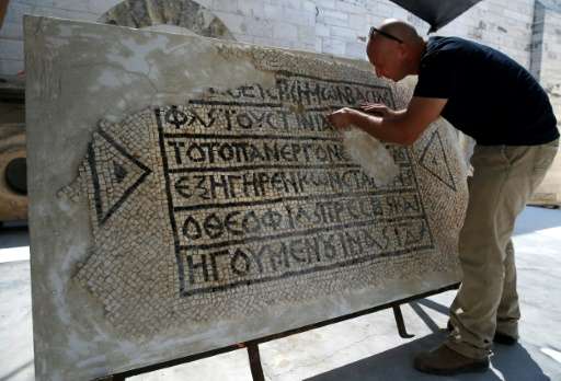 An archaeologist works on a 1,500-year-old section of floor mosaic bearing the name of Byzantinian Emperor Justinian, at the Roc