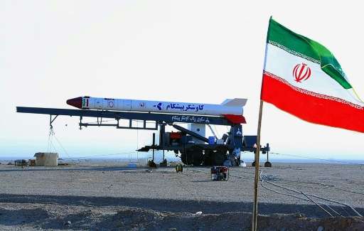 An Iranian flag flutters in front of one of the the Pishgam (Pioneer) capsules that carried the monkeys into space in this pictu