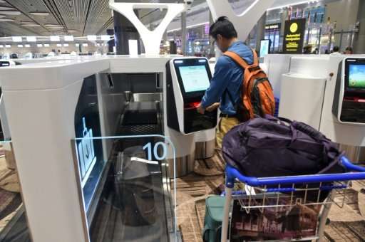 A passenger checks-in his luggage using an automated booth at the newly opened Changi International Airport's Terminal 4 in Sing