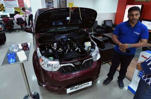 A sales executive talks about Mahindra's electric car &quot;e2o Plus&quot;, on display at a showroom in New Delhi