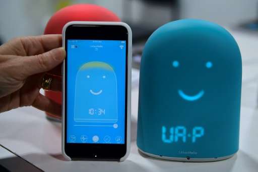 A smartphone is placed next to Remi—a smart alarm clock for kids which offers a night tracke and a storyteller—on display at the