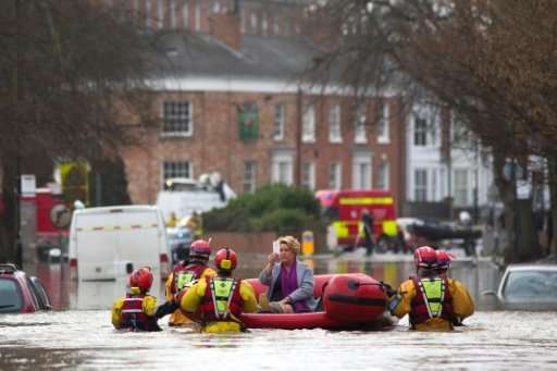 A woman takes a photograph as she is transported to safety by members of the emergency services, after homes were affected by fl