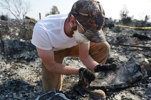 Ben Pederson looks at a burnt school yearbook after his family's home was destroyed by wildfire in Santa Rosa, California