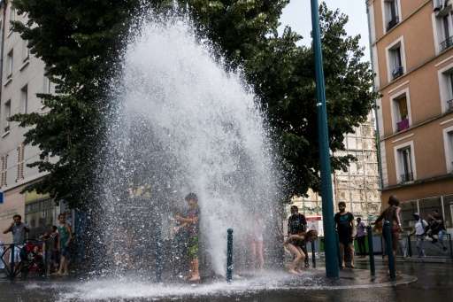 Children in Paris cool off at an open fire hydrant as France sizzles, having hit its hottest June day since 1945 on Wednesday