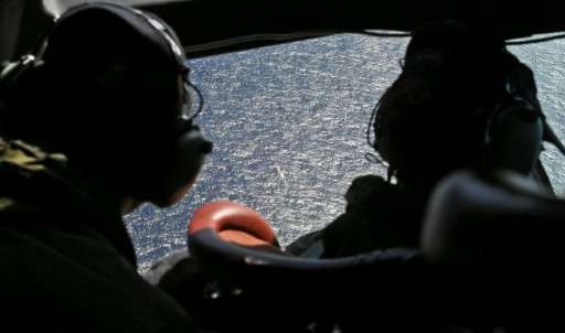 Crew members looking out the cockpit windows of a RNZAF P3 Orion during search operations for wreckage and debris of missing Mal