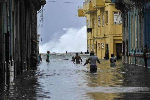 Cubans wade through a flooded street near the Malecon seafront promenade in Havana, on September 10, 2017.