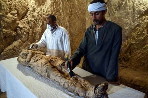 Egyptian archaeological technicians restore a mummy wrapped in linen, found at Draa Abul Naga necropolis on the west bank of the