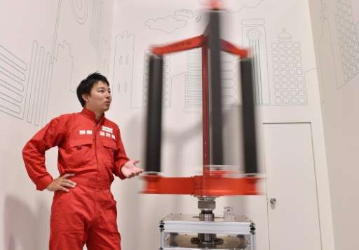 Engineer Atsushi Shimizu, founder and CEO of the Japanese venture company Challenergy, stands next to his bladeless wind turbine