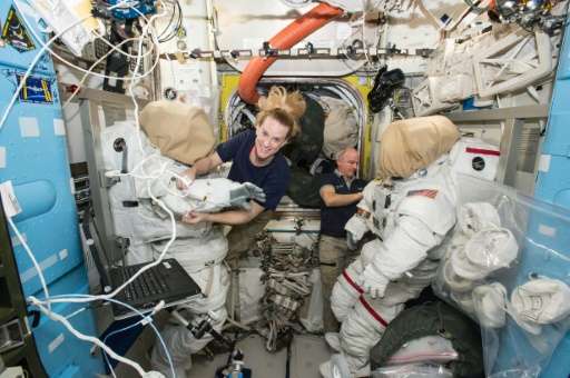 Expedition 48 crew members Kate Rubins and Jeff Williams (R) of NASA outfit spacesuits inside of the Quest airlock aboard the In