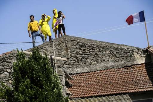 Fans watch the race from the roof of a house during the 165km, 16th stage of the 104th edition of the Tour de France between Le 