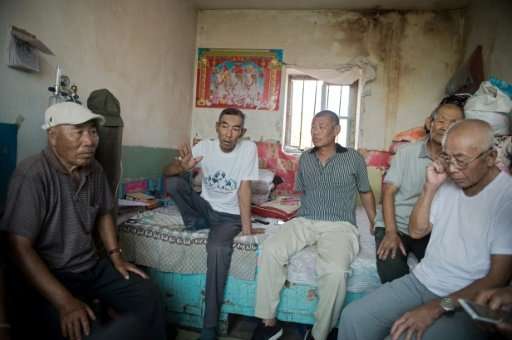 Farmer Wang Enlin (2nd L) sits in his house with fellow environmental activists who have taken on a subsidiary of China's larges