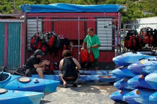 Jose Figueroa (R) and two others clean kayaks and equipment used for tours to the bioluminescent bay in Fajardo, Puerto Rico—one