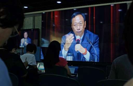 Journalists (in foreground) watch a large video screen showing Terry Gou, founder of Foxconn parent Hon Hai group, during a shar