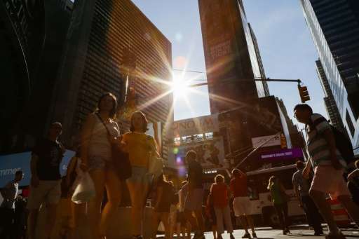 People walk around Times Square during a sunny day as hot temperatures continue in New York on July 21, 2017