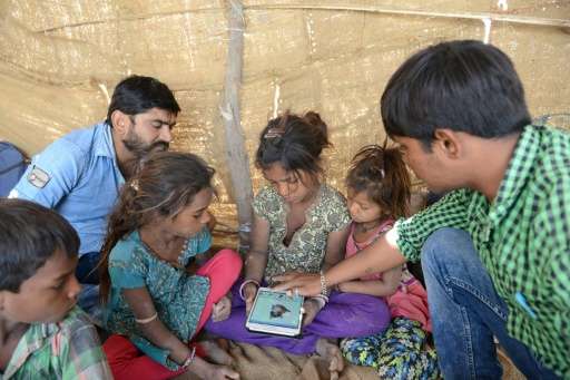 Sheltered beneath a canvas sheet, miles from any roads or power lines, children huddle around a tablet and experience the intern